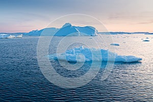 Photogenic and intricate iceberg under an interesting and blue sky during sunset. Effect of global warming in nature.