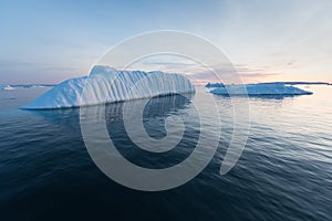 Photogenic and intricate iceberg under an interesting and blue sky during sunset. Effect of global warming in nature.