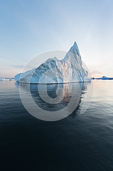 Photogenic and intricate iceberg under an interesting and blue sky during sunset. Effect of global warming in nature.