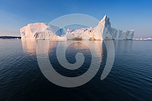 Photogenic and intricate iceberg under an interesting and blue sky during sunset. Effect of global warming in nature.