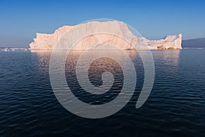 Photogenic and intricate iceberg under an interesting and blue sky during sunset. Effect of global warming in nature.