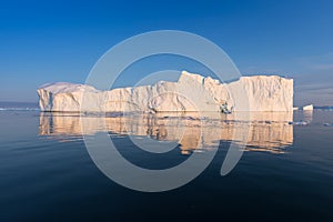 Photogenic and intricate iceberg under an interesting and blue sky during sunset. Effect of global warming in nature.