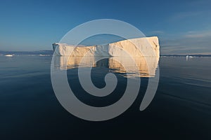 Photogenic and intricate iceberg under an interesting and blue sky during sunset. Effect of global warming in nature.