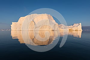 Photogenic and intricate iceberg under an interesting and blue sky during sunset. Effect of global warming in nature.