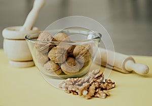 Photograph from above of a still life mounted on a yellow background and composed of a kneader, a glass bowl and some nuts