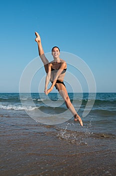 Photograph of a beautiful female dancer jumping on a beach in t