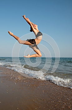 Photograph of a beautiful female dancer jumping on a beach in t