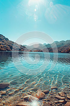 photograph of the beautiful lake with clear water, surrounded hills and mountains