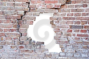 Photograph of a broken porous old brick wall with hole after accident