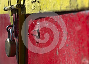 A photograph of a colorful closed metal door with a padlock.