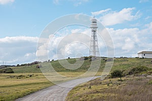 Photograph of Currie Lighthouse on a hill against a cloudy bright blue sky on King Island