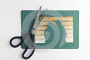 Photograph with cut out people with scissors on green cutting ma