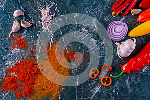 Assortment of peppers, garlic and onions on a stone countertop