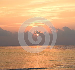 Rising Golden Sun from Dark Clouds at Horizon over Sea with Bright Sunshine and Colorful Sky