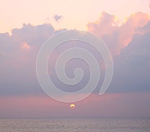 Golden yellow sun setting over ocean with dark clouds in bright pinkish sky - Laxmanpur, Neil Island, Andaman, India