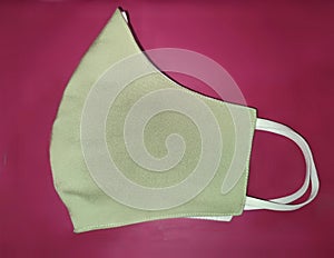 Photograph of green mask with white strap in pink red mauve background