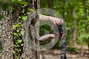 Photograph hidden behind the tree in forest peeking with camera