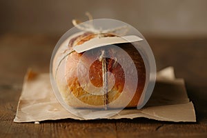 A photograph of a loaf of bread completely wrapped in brown paper, highlighting the packaging of the bread, Bread loaf with a