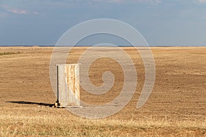 Photograph of an old rural outhouse or toilet in steppe. Single wooden building