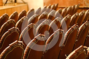 Photograph of the Rows of theatre seats. beige soft velvet chairs in the theater hall