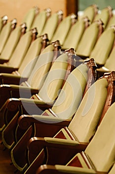 Photograph of the Rows of theatre seats. beige soft velvet chairs in the theater hall