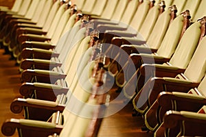 Photograph of the Rows of theatre seats. beige soft velvet chairs in the theater hall