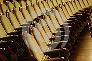 Photograph of the Rows of theatre seats. beige soft velvet chairs in the theater hall