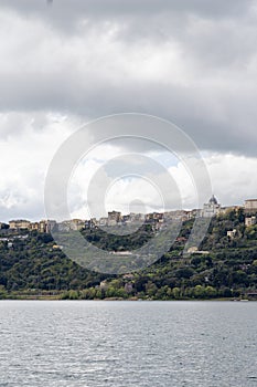 Photograph taken in Castel Gandolfo, Italy, featuring a view of the lake and mountains with a distant cityscape