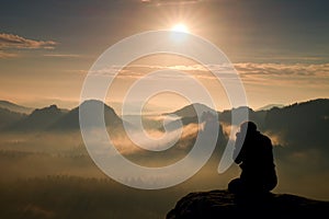 Photograph takes photos of daybreak above heavy misty valley. Landscape view of misty autumn mountain hills and happy man silhoue