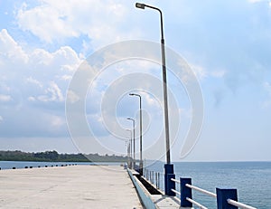 Uncrowded Ferry Jetty with Poles of Light in Open Sea and Cloudy Sky photo
