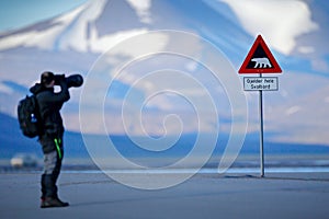 Photographer with big lens and road traffic sign with Polar bear. Ã¯Â¿Â½Gjelder Hele Svalbard means Over All of Svalbard watch out f photo