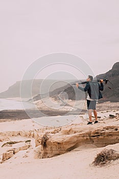 Photographer with camera looking for motive of unique landscape. Sand dunes and volcanic cliffs on the Atlantic