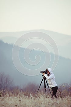 photographer with camera and tripod outdoor taking landscape picture