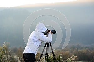 photographer with camera and tripod outdoor taking landscape picture