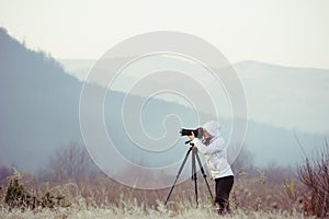 photographer with camera and tripod outdoor taking landscape picture