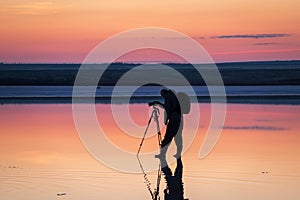 Photographer capturing sunset over tranquil waters