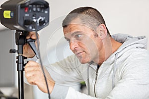 photographer controlling studio flash strobe lighting head