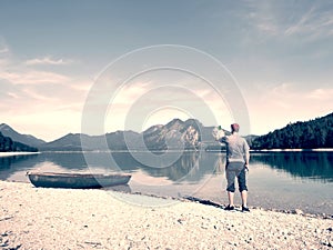 Photographer with eye at viewfinder is taking photo of lake with Alps