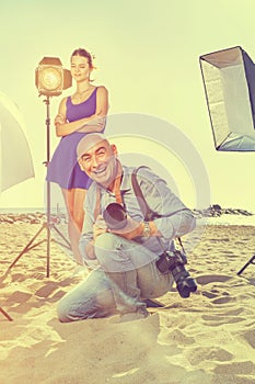 Photographer with female model on sea coast