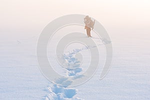 Photographer on a foggy day in winter with snow and tracks