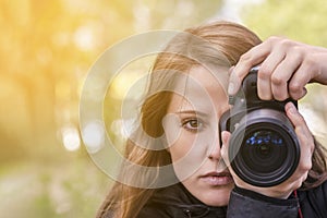 Photographer girl, close-up portrait. The girl model takes photos, looking at the viewer and into the lens of the