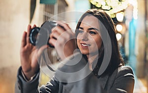 Photographer girl with retro camera take photo on background bokeh light in night city, Blogger photo hobby. Outdoor portrait of