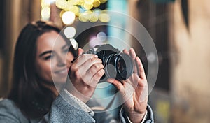 Photographer girl with retro camera take photo on background bokeh light in night city, Blogger photoshoot concept. Tourist