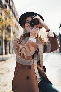 Photographer in glasses take photo on retro camera. Tourist portrait. Girl in hat travels in Barcelona holiday. Sunlight flare