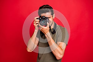 Photographer guy with photo digicam making pictures wear casual grey t-shirt isolated on red background