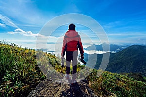 Photographer hand holding camera and standing on top of the rock in nature. Travel concept