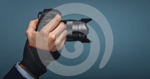 Photographer hand holding dslr camera on blue modern backround