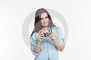 Photographer, hobby and people concept - Young brunette woman with retro camera on white background