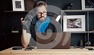 Photographer holding camera looking laptop