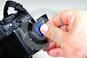 Photographer inserting or removing a blue memory card into the slot in the camera